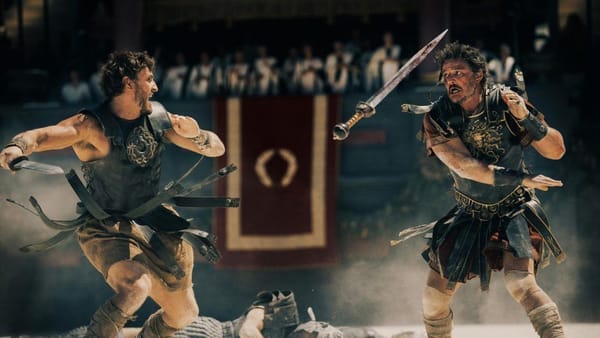 two men on each side of the screen in roman battle armor fighting with roman swords from Gladiator II