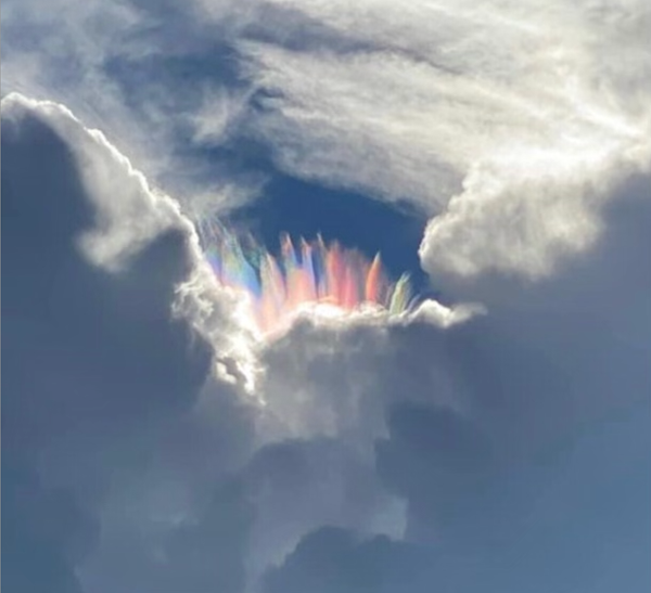 rainbow shard like crystals in clouds with blue sky around it.