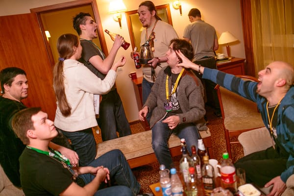 A group of nerdy 7 young white guys (and one girl) in lanyards in a hotel room drinking and partying. 